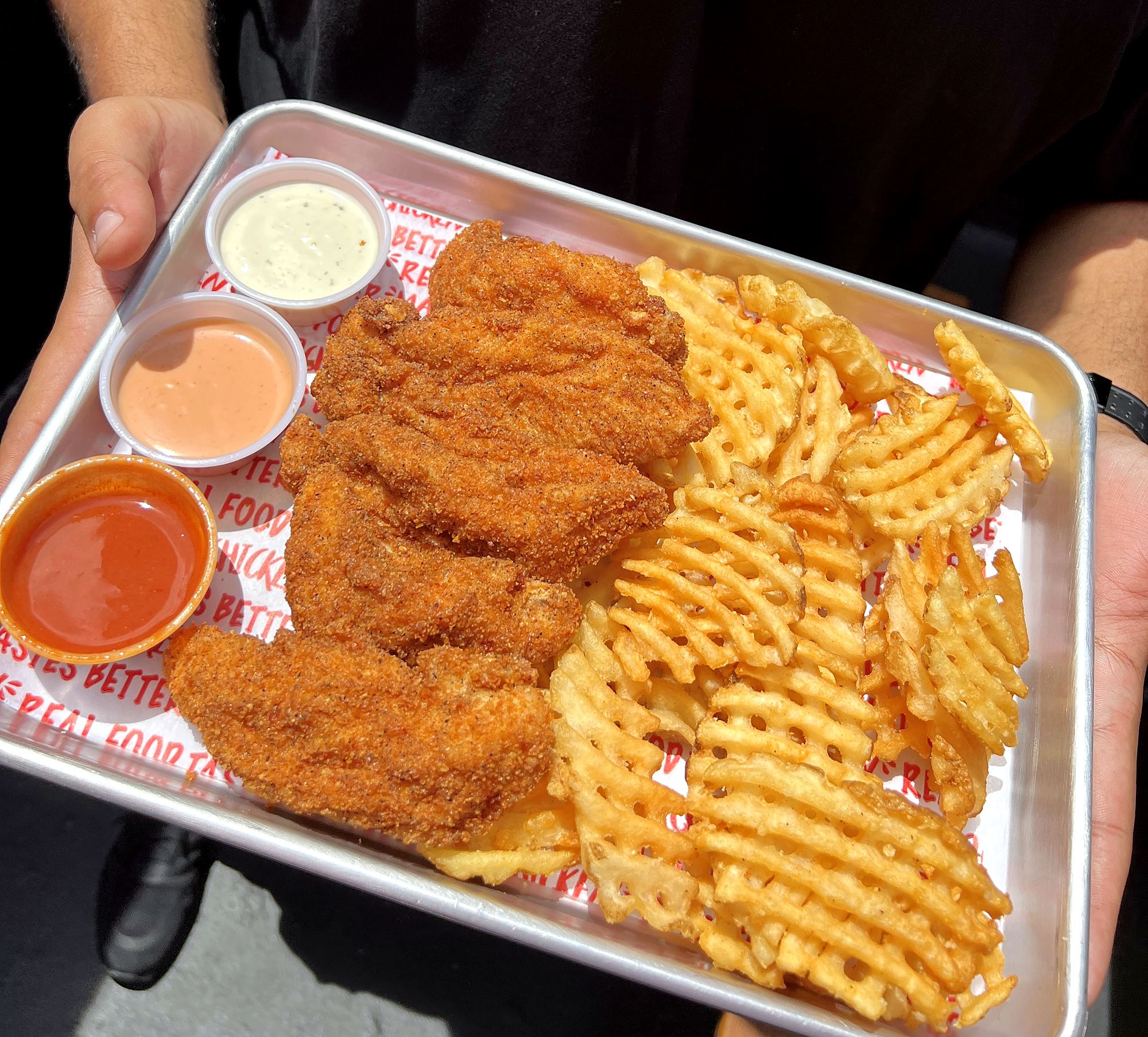 Tenders and waffle fries on a tray
